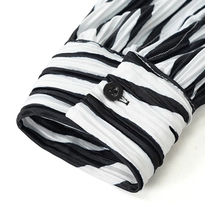 Detailed close-up of pleated zebra print sleeves with black button on a long sleeve shirt