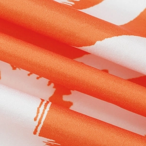 Detailed macro shot showing the orange and white abstract print on satin-like fabric texture