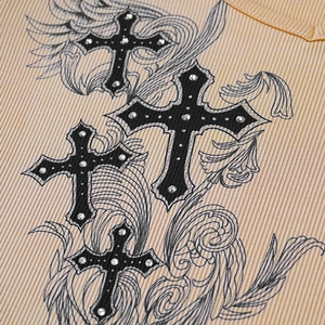 Close-up of ribbed knit fabric with gothic cross prints and sparkling rhinestone details