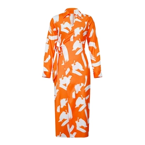 Detailed close-up of orange wrap maxi dress with white abstract print and V-neckline