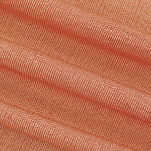 Détail macro du tissu en maille côtelée orange corail avec motif à rayures verticales