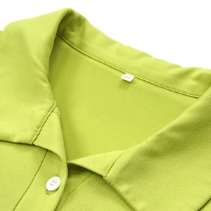 Detail shot of green knitted polo shirt showing the collar, white button and size S tag