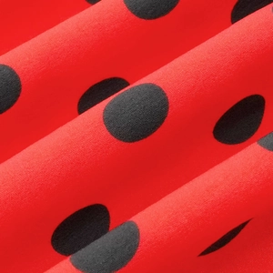 Détail de tissu rouge à pois noirs avec une texture tissée fine et douce