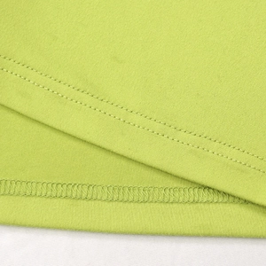 Close-up of high-quality double-needle stitching and overlock seams on green knitted dress