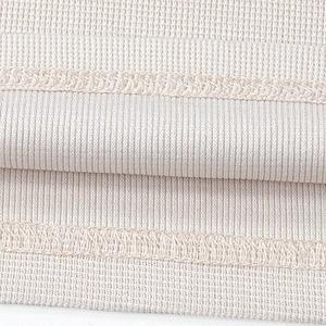 Detailed close-up of beige waffle knit fabric texture and high-quality overlock stitching