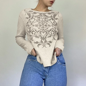 Macro detail of beige waffle knit long sleeve top with vintage heraldic crest print
