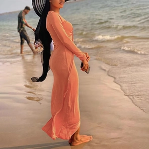 Robe longue élégante rose pêche à col en V, manches longues et fente haute sur la plage