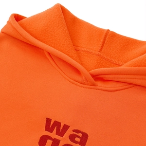Detail eines orangefarbenen Kapuzenpullovers mit Stickerei und weichem Fleece-Futter