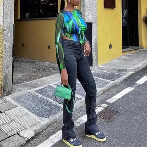 Détail d'un haut en mesh imprimé multicolore avec un pantalon noir et un sac à main vert
