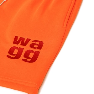 Nahaufnahme der roten Logostickerei auf orangen Strickshorts aus weichem Baumwollstoff