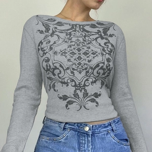 Detail of grey waffle knit long sleeve top with vintage scrollwork print and boat neck