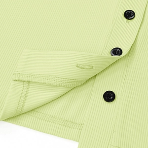 Detailed view of light green ribbed knit fabric featuring classic black round buttons