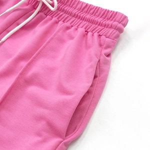 Dettaglio dei joggers rosa a vita alta con elastico in vita, coulisse bianche e tasche