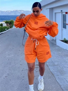 Detail des orangefarbenen Hoodie-Sets mit besticktem Logo und Kordelzug-Shorts