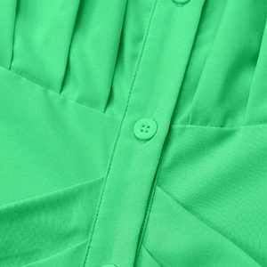 Detail of bright green short sleeve dress featuring matching resin buttons and neat stitching