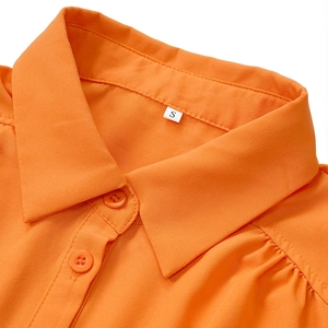 Detail eines orangefarbenen Hemdkragens mit Knöpfen, Puffschulter und Größenetikett