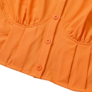 Detailansicht der hellorangen Bluse mit passenden Knöpfen und feinen Falten-Details
