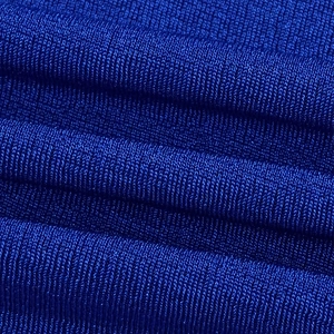 Macro shot of royal blue knit fabric with fine ribbed texture and elegant draped waves