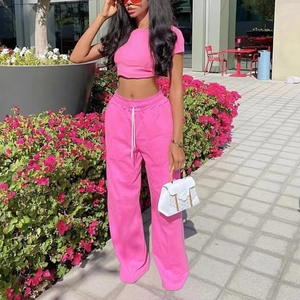 Completo donna con pantaloni a gamba larga a vita alta rosa e crop top in ambiente urbano
