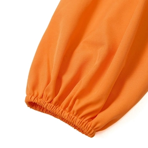 Detailaufnahme der orangefarbenen Blusenärmel mit elastischen Bündchen und Webstruktur