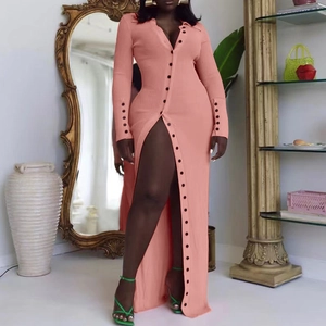 Detail view of pink-orange ribbed knit dress with black front buttons and a high slit