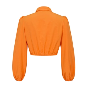 Detail des orangefarbenen Crop-Tops mit Puffärmeln und elastischem Saum an der Taille