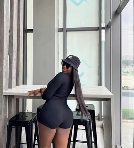 Detail of a slim fit black long sleeve romper paired with a branded bucket hat in a street setting