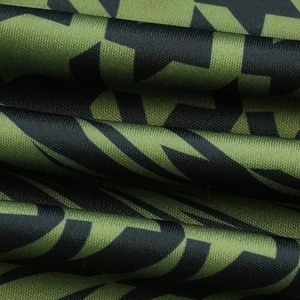 Close-up of the smooth fabric with abstract geometric print on a green background