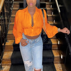 Detail einer leuchtend orangefarbenen Kurzbluse mit Puffärmeln und Knopfleiste