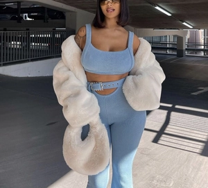 Détail d'un ensemble en tricot bleu clair avec ceinture strass et manteau en fourrure