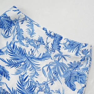 Gros plan détaillé sur l'imprimé floral et tropical du haut de la jupe bleue et blanche
