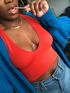 Détail du haut court en tricot côtelé orange avec un cardigan bleu et un jean en denim