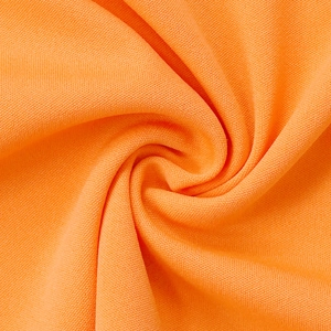 Detailed close-up showing the fine knit texture and soft orange fabric of the sports set