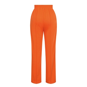 Detail view of bright orange high-waisted trousers with elastic waistband and vertical seams