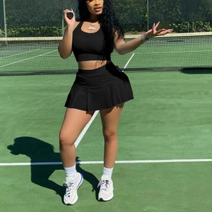 Women's black athletic two-piece set featuring a halter crop top and pleated tennis skirt