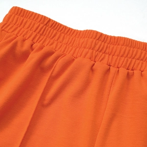 Detail of high waist elastic waistband with parallel stitching on orange trousers