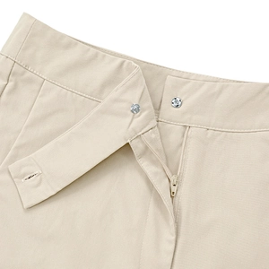 Detailed shot of the metal zipper and snap button closure on beige casual wide-leg trousers