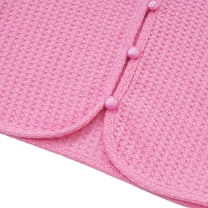Nahaufnahme der rosa Waffelstrickstruktur und Perlmuttknöpfe am sexy Crop-Top für Damen