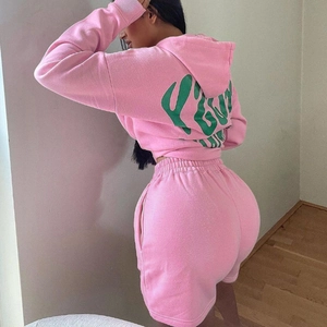 Detail view of pink hoodie set featuring green puff print logo and soft cotton texture