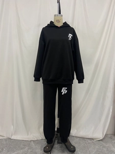 Detail view of black hooded sweatsuit featuring silver geometric logo on an athletic mannequin