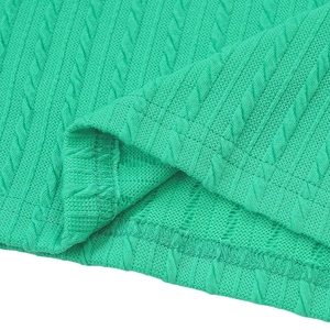 Close-up of green knitted dress fabric showing detailed texture and cable stitch patterns
