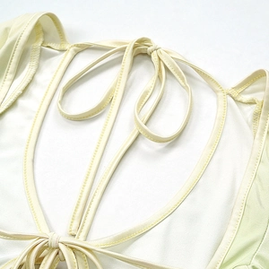 Detailed macro view of the delicate yellow satin fabric with lace-up straps and fine stitching