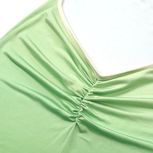 Detail of sexy deep V-neck dress with light green fabric and elegant central ruching