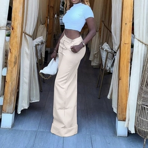 Detail of high waisted wide leg trousers in apricot featuring side pockets and fluid drape