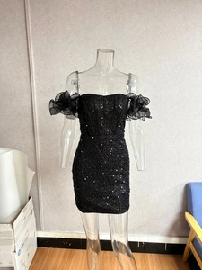 Close-up of black sequined dress with sheer organza ruffled sleeves and off-shoulder design