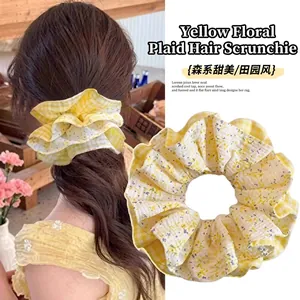Detail showing yellow floral and checkered scrunchie styled on a girl's high ponytail
