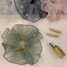 Detail of sheer organza spiral hair ties and yellow clips with elegant pearl accents