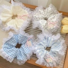 Detail of four lace-edged hair scrunchies in milk tea tones on a wooden surface
