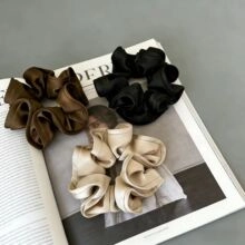 Close-up of satin scrunchies in coffee black and champagne colors on a magazine