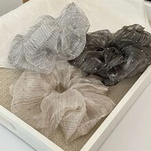Close-up of pleated Swiss dot sheer fabric scrunchies set in grey and beige tones